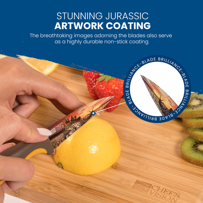 A hand slices a lemon with a Chef's Vision Jurassic Six-Piece Knife Set, which features a dinosaur design on the stainless steel blade; kiwifruit slices and a whole strawberry sit nearby on a wooden cutting board.