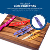 Displayed on a wooden cutting board are various colorful BladeKeepers Blade Covers from the Landscape Series Knife Set by Chef's Vision, with a close-up inset highlighting a blue cover.