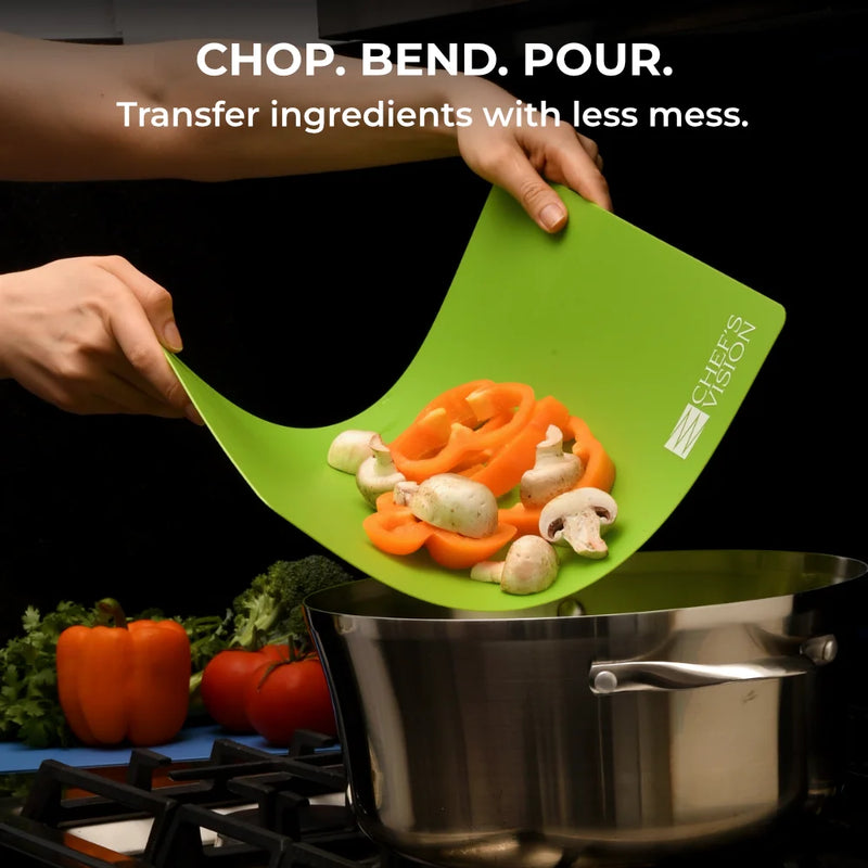 A person bends a green SliceBright Flexible Cutting Mat from Chef's Vision to pour sliced bell peppers and mushrooms into a pot on the stove. This set of six color-coded mats is dishwasher safe, making kitchen cleanup quick and easy.