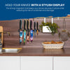 A vibrant kitchen decor showcases the BEHOLD Wall-Mounted Magnetic Knife Holders by Chef's Vision, which elegantly display colorful knives above a countertop equipped with a sink, basket, and hanging utensils.