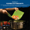 Using a Slice Bright Flexible Cutting Mat from Chef's Vision, a person carefully pours chopped vegetables into a pot on the stove, with colorful peppers visible nearby.