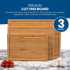 The Chef's Vision Slice Bright Bamboo Cutting Boards - Set of 3, featuring various sizes, are showcased on a marble surface alongside tomatoes and garlic.