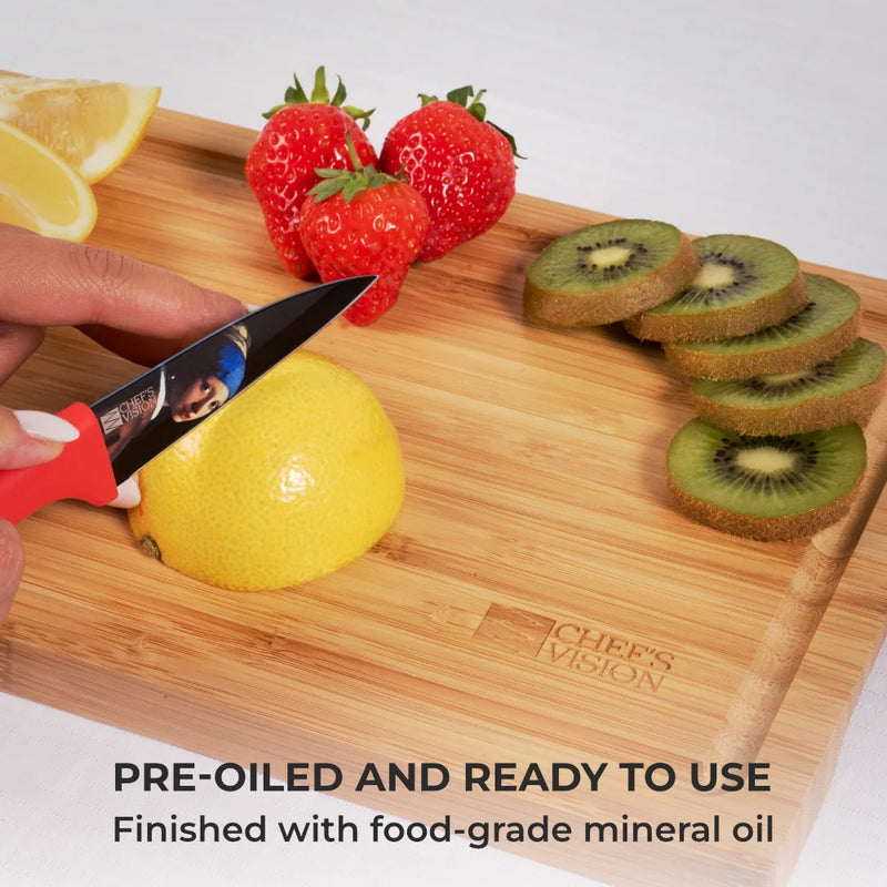 A hand slices a lemon on the Chef's Vision SliceBright Moso Bamboo Cutting Board, surrounded by strawberries, kiwi slices, and lemon wedges. Text reads: "Pre-oiled and ready to use. Finished with food-grade mineral oil." Set of 3 included.