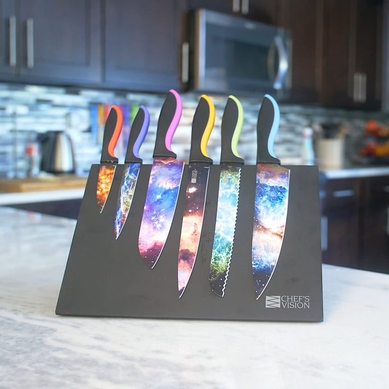 The Chef's Vision Cosmos Six-Piece Knife Set features stainless steel blades with vibrant galaxy designs and non-stick coating, displayed in a sleek black block on your kitchen counter.