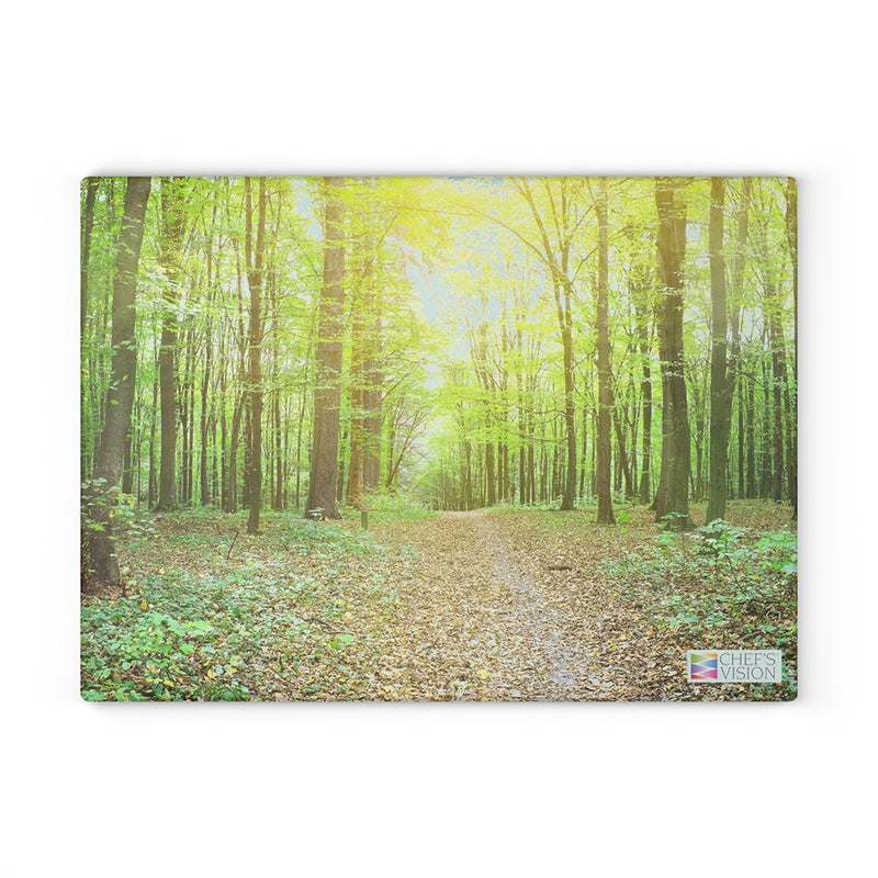 A SliceBright Landscape Glass Cutting Board in the woods with sunlight shining through the trees, created by Chef's Vision.