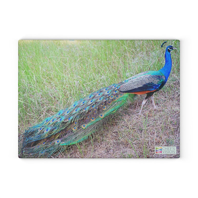 A peacock is standing on a Chef's Vision SliceBright Wildlife Glass Cutting Board in the grass.