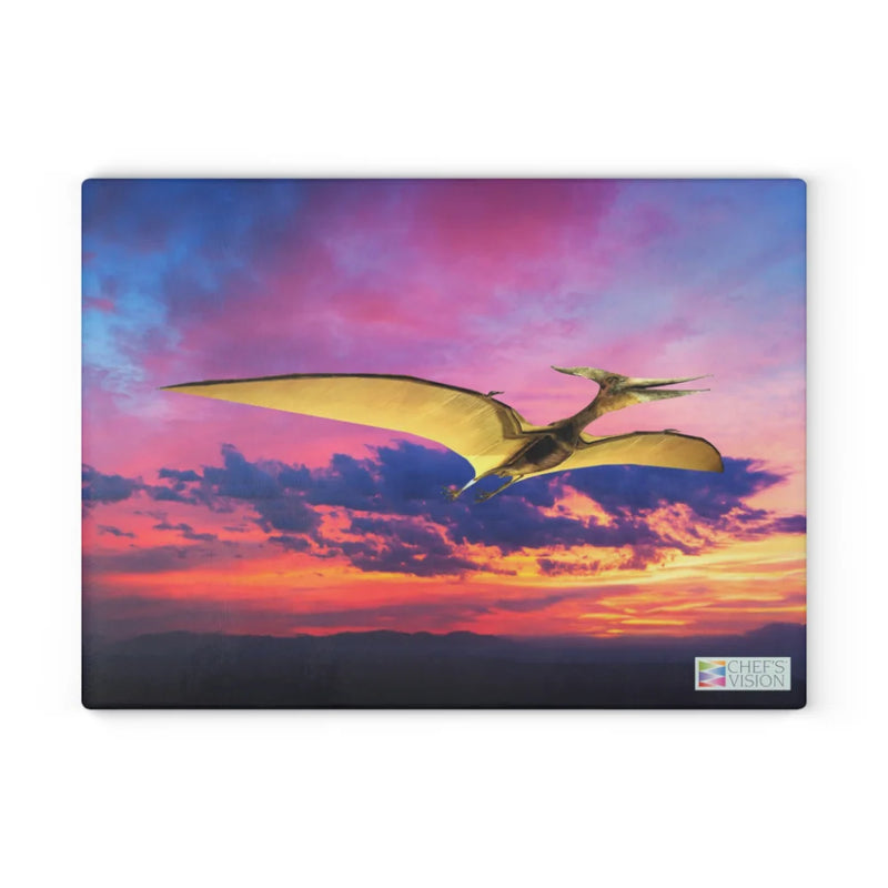 A flying pterosaur soars against a vibrant sunset over silhouetted mountains—dinosaur artwork on the SliceBright Jurassic Glass Cutting Board by Chef's Vision, perfect for brightening any kitchen. The Chef's Vision logo adorns the corner.