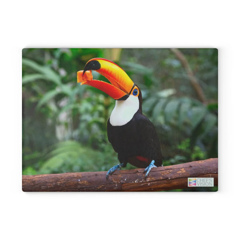 A toucan with a large orange beak sits amid green foliage, inspiring the Chef's Vision SliceBright Wildlife Glass Cutting Board—ideal for adding vibrant wildlife art to your kitchen.