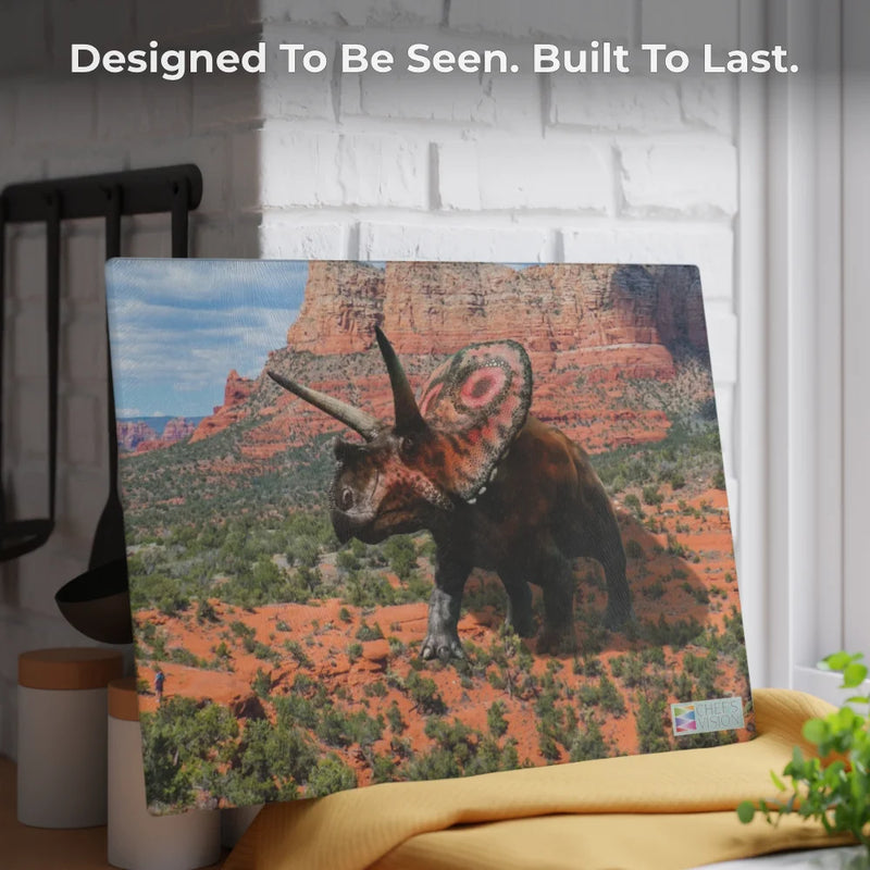 The Chef's Vision SliceBright Jurassic Glass Cutting Board, featuring striking Triceratops art in a desert landscape, sits on a kitchen counter with the words, "Designed To Be Seen. Built To Last." displayed above.