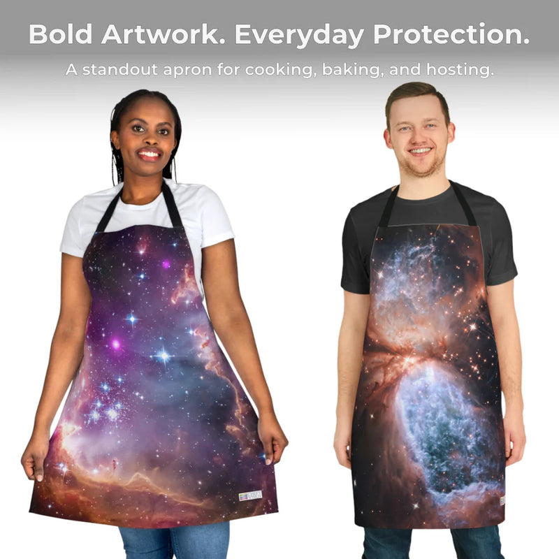 Two people wear Chef's Vision Cosmos Aprons, featuring vibrant space-inspired artwork, as they stand side by side and smile against a light gray background.