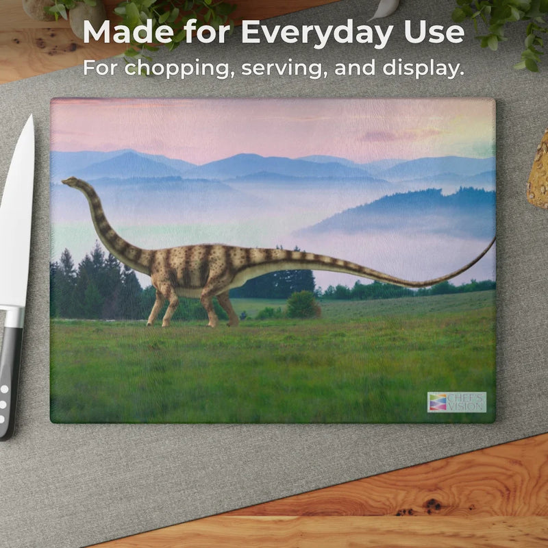 The Chef's Vision SliceBright Jurassic Glass Cutting Board features vibrant dinosaur art with a long-neck in a grassy field—perfect for your kitchen. Includes knife & napkin. Text: "Made for Everyday Use.