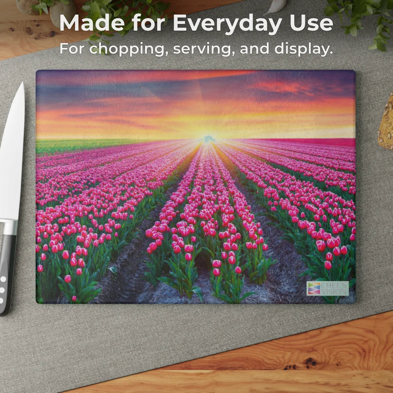 The Chef's Vision SliceBright Landscape Glass Cutting Board, featuring a vibrant tulip field scene, rests on a wooden kitchen counter beside a knife—perfect for everyday use.