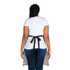 The back view of a woman wearing jeans and a Chef's Vision Masterpiece Apron.