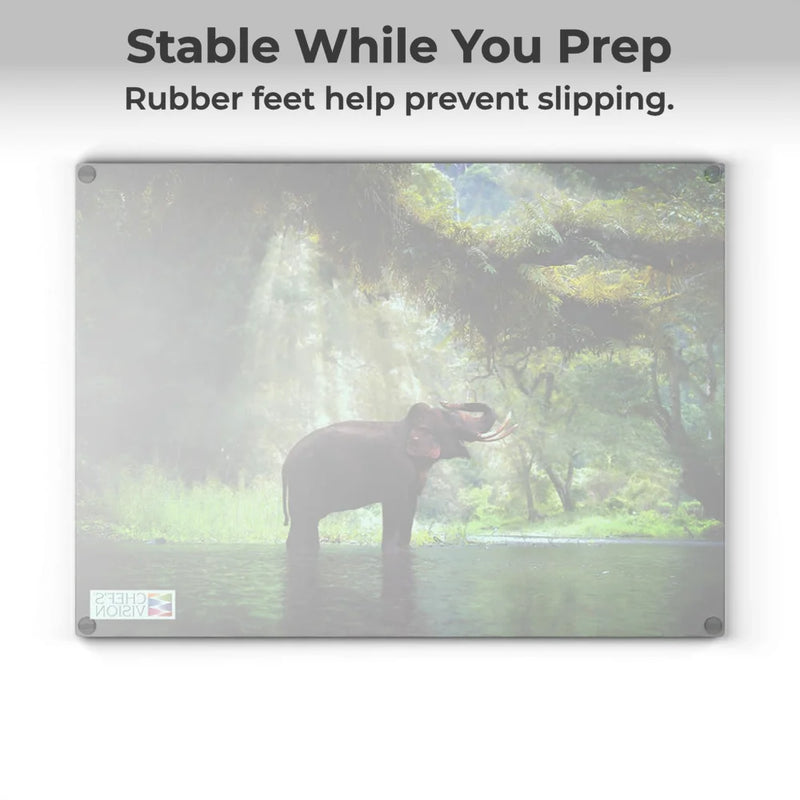 The Chef's Vision SliceBright Wildlife Glass Cutting Board features vivid elephant-in-water art and “Stable While You Prep” text. Its rubber feet help prevent slipping, blending functional art with practicality.