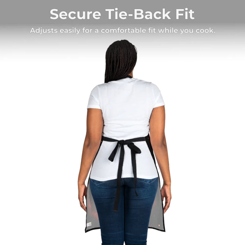 A person models the Chef's Vision Cosmos Apron, made of durable polyester canvas, in white shirt and blue jeans. The apron features a secure, adjustable tie-back fit for comfort while cooking.